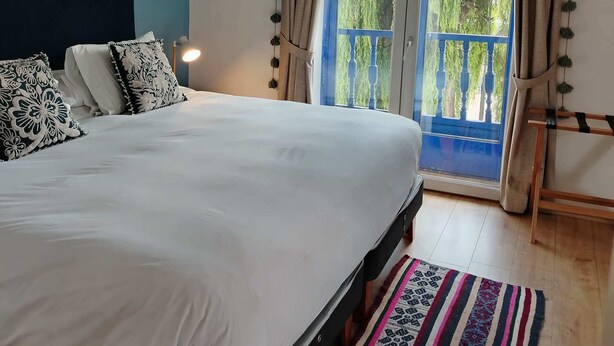 A bedroom with a large bed, a view of a balcony, and a patterned rug. - w* | Modern 1BR in Plaza de Armas w/ Balcony (Cusco)
