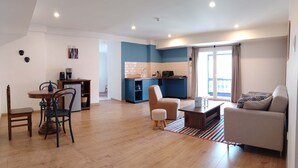 A spacious living area with a dining table, chairs, a sofa, and a kitchen in the background. - w* | Modern 1BR in Plaza de Armas w/ Balcony (Cusco)