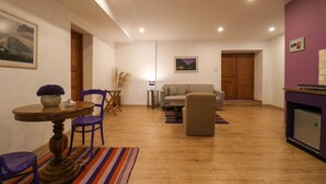 Een woonkamer met een houten vloer, een ronde tafel met stoelen, een bank en een paars accentmuur.