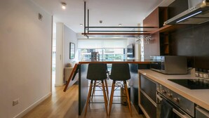 Una cocina moderna con una isla central, taburetes de bar y electrodomésticos integrados.