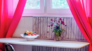 A small kitchen area with a white countertop, a bowl of fruit, a potted plant, and a window with wooden shutters. - Studio Apartment Silvana (Split)