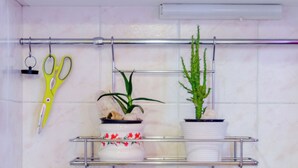 A kitchen with a stainless steel sink, a faucet, and two potted plants on a metal shelf above the sink. - Studio Apartment Silvana (Split)