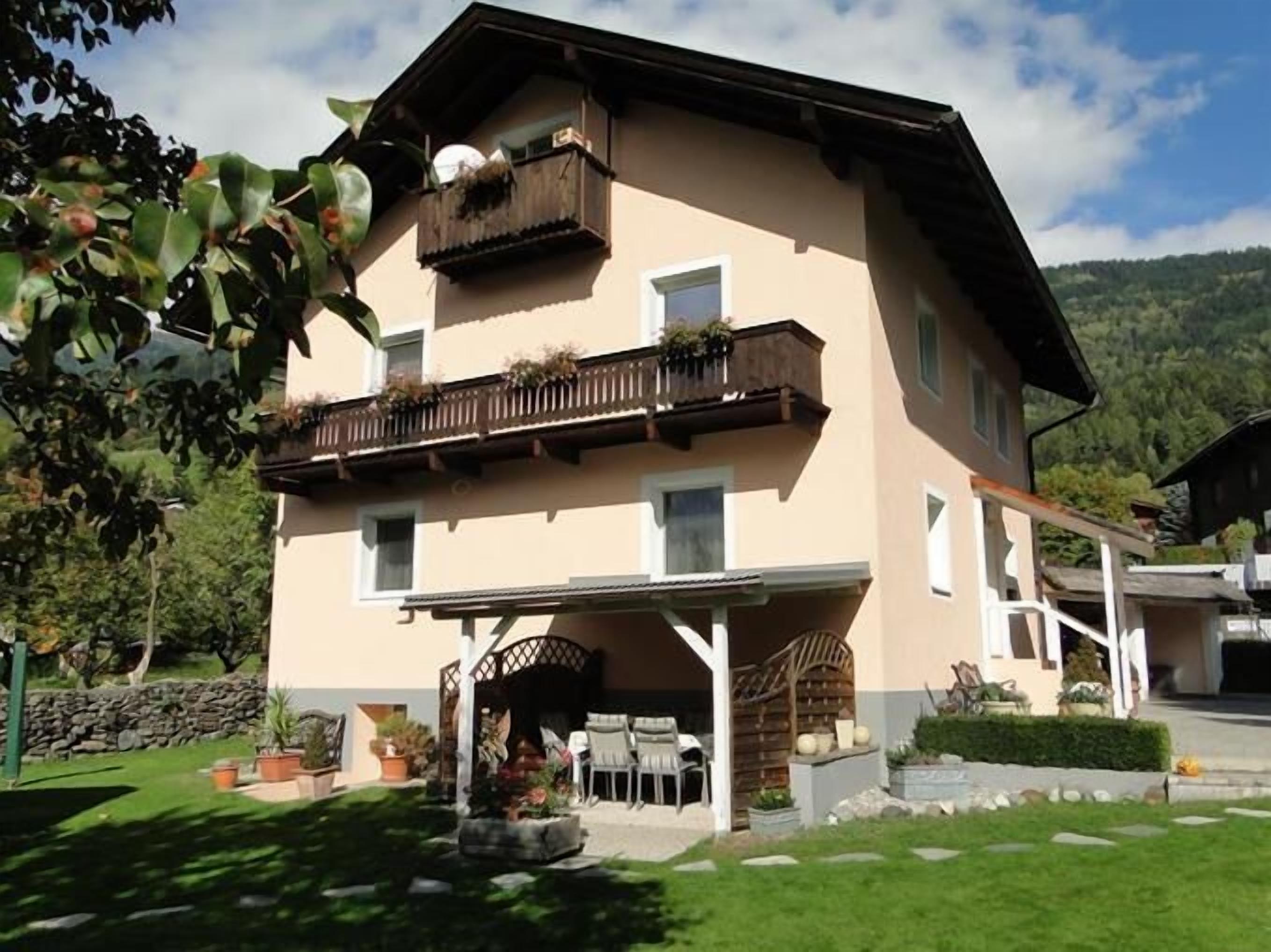 A two-story building with a balcony, a covered patio, and a stone wall.