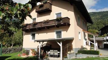 A two-story building with a balcony, a covered patio, and a stone wall.