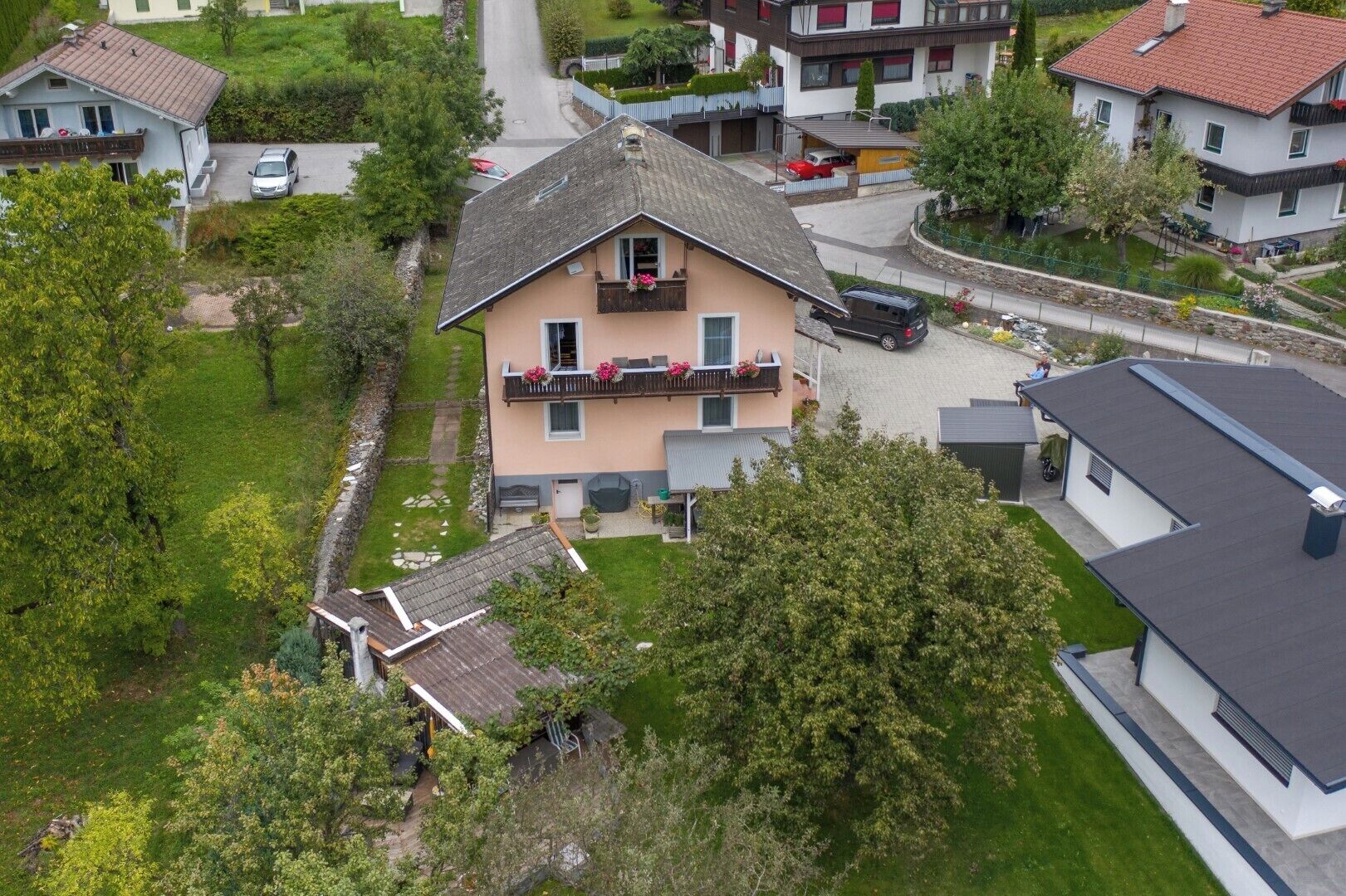 A two-story house with a balcony, a driveway, and a garden.