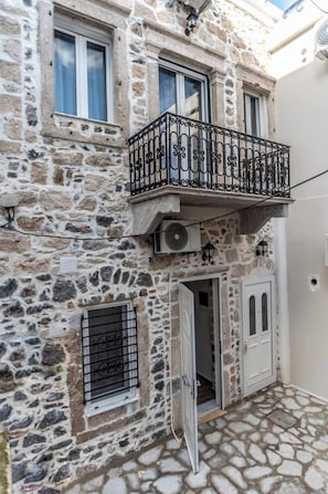 A stone building with a balcony, a door, and a window.