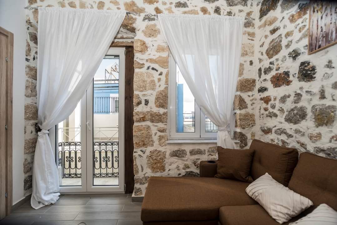 A room with stone walls, a brown sofa, and white curtains.