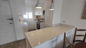 A modern kitchen with white cabinetry, a large island, and pendant lighting. - AP394-VERDEMAR 46 (Nerja)