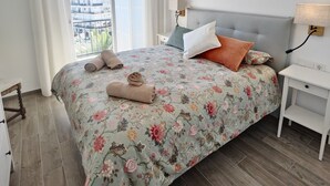 A bedroom with a bed, a ceiling fan, a nightstand, a lamp, and a view of the outside. - AP394-VERDEMAR 46 (Nerja)