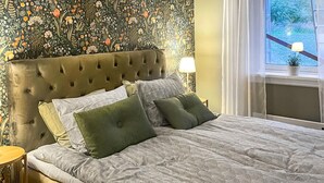 A bedroom with a tufted headboard, a patterned bedspread, and a floral wallpaper. - 2 bedroom amazing home in Säffle (Säffle)
