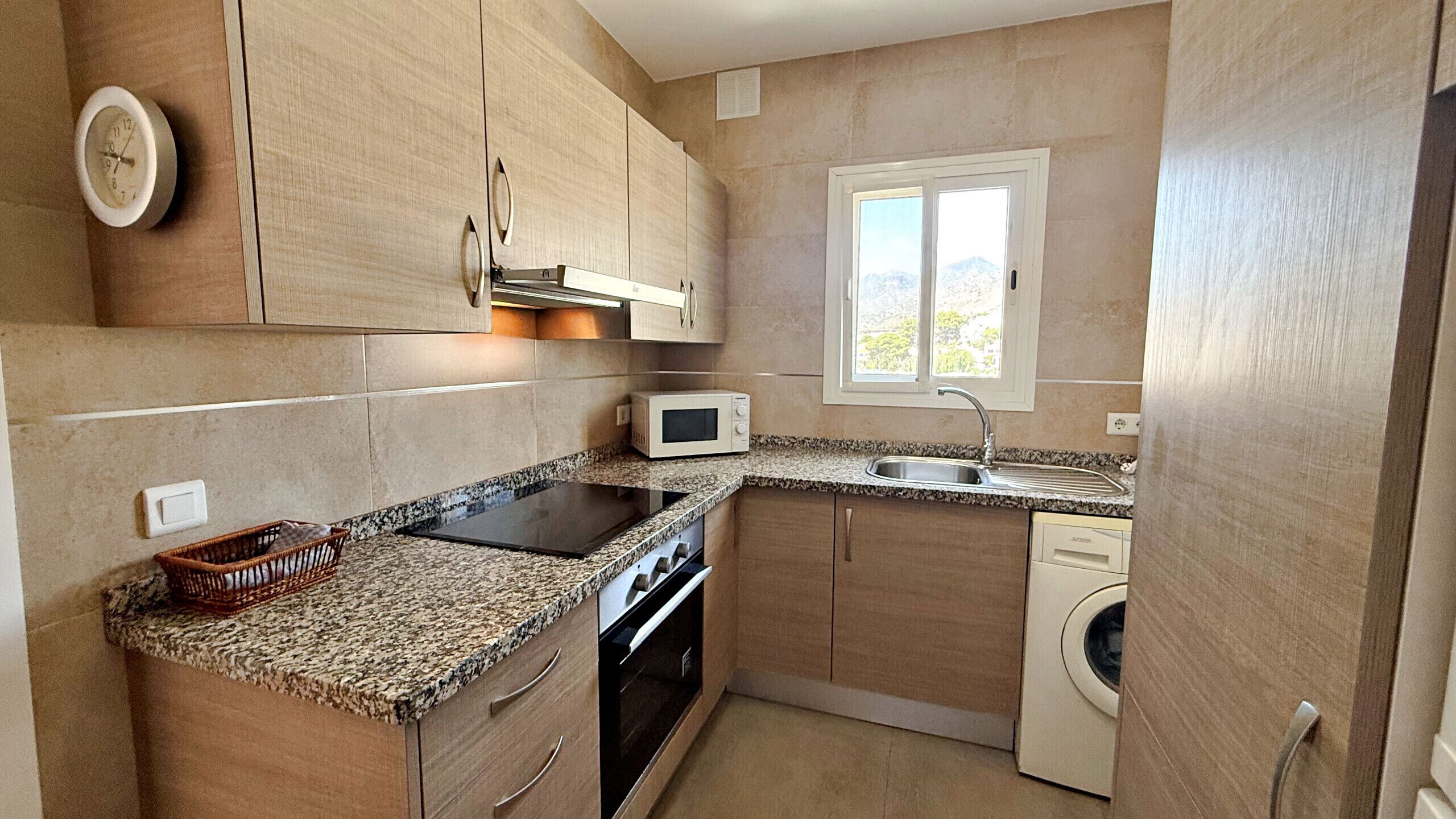 A compact kitchen with a microwave, sink, stove, and washing machine.