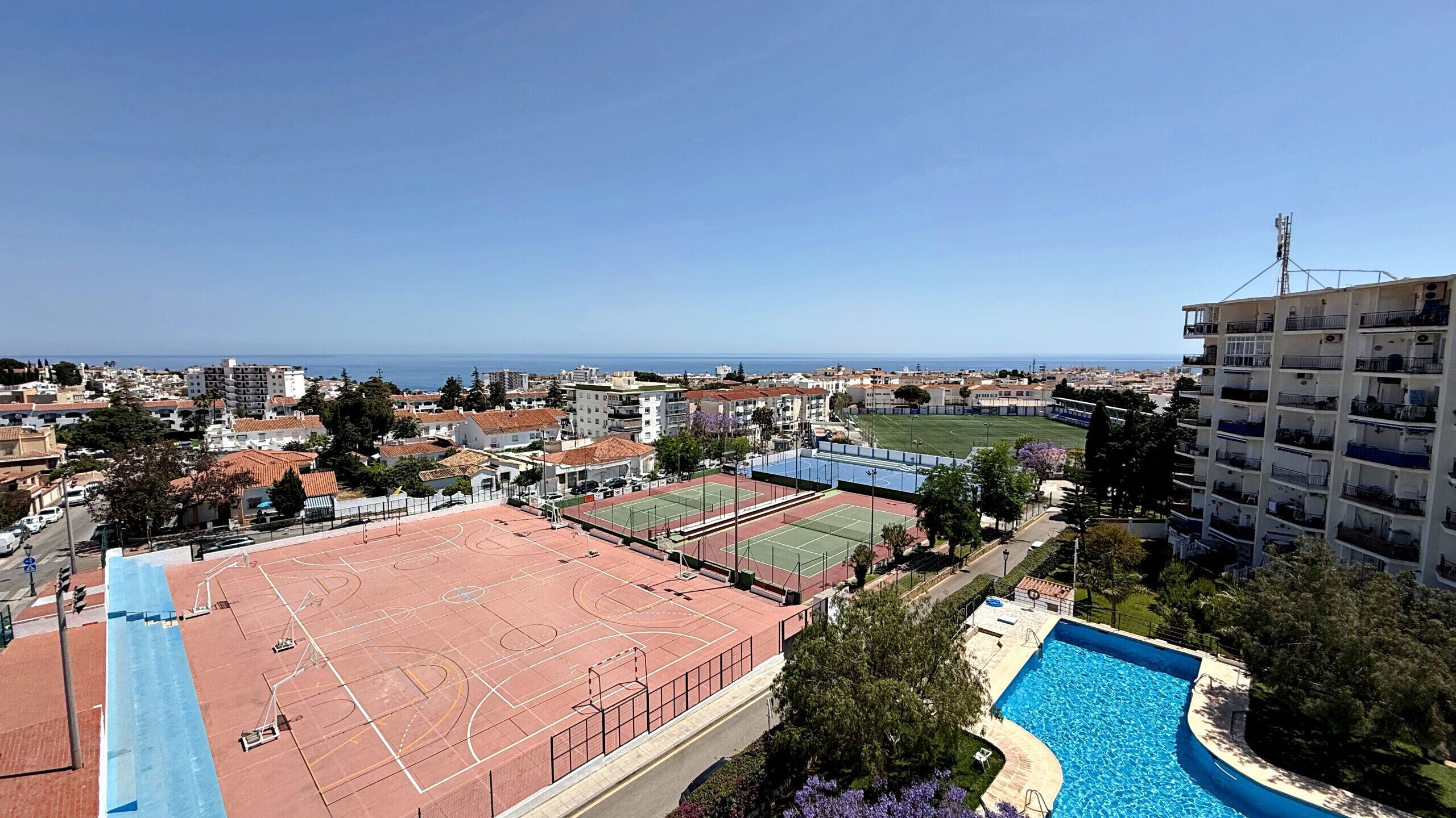 Ein Wohngebiet mit Schwimmbad, Tennisplätzen und Meerblick.