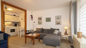 Een gezellige woonkamer met een bank, een salontafel en een eethoek met een stoel en tafel.