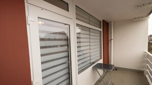 Een balkon met ruiten met geëtste glasschijven, een kleine tafel en een hekwerk.