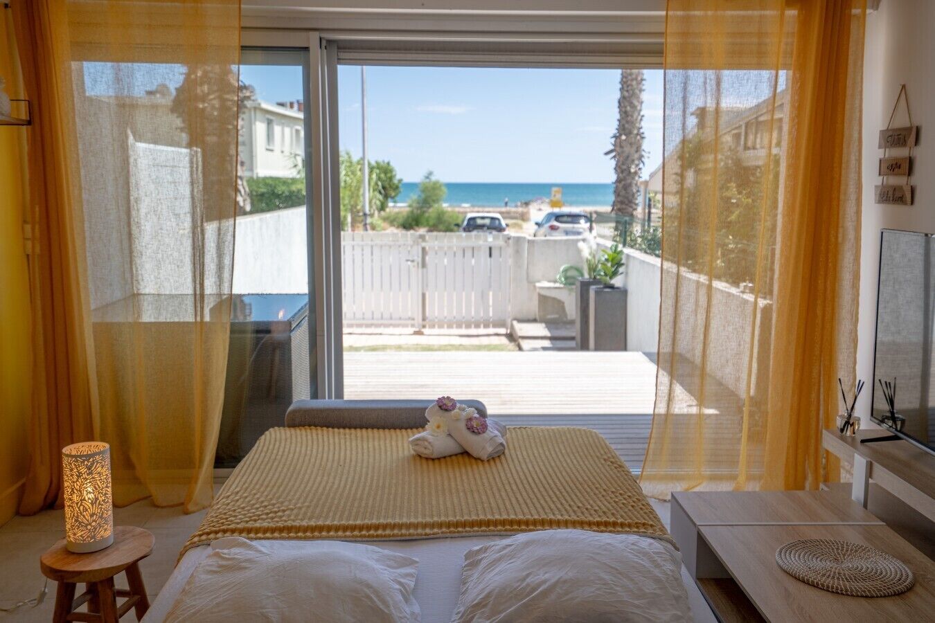 Un dormitorio con una cama grande, vista al mar y un balcón con valla blanca.