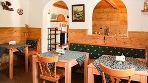 A rustic dining area with wooden tables and benches, a wooden shelf with dishes, and a framed painting on the wall. - Ferienwohnung Hochkalter, Dusche/wc, 57 qm, TV, Balkon, Obergeschoss (Ramsau bei Berchtesgaden)