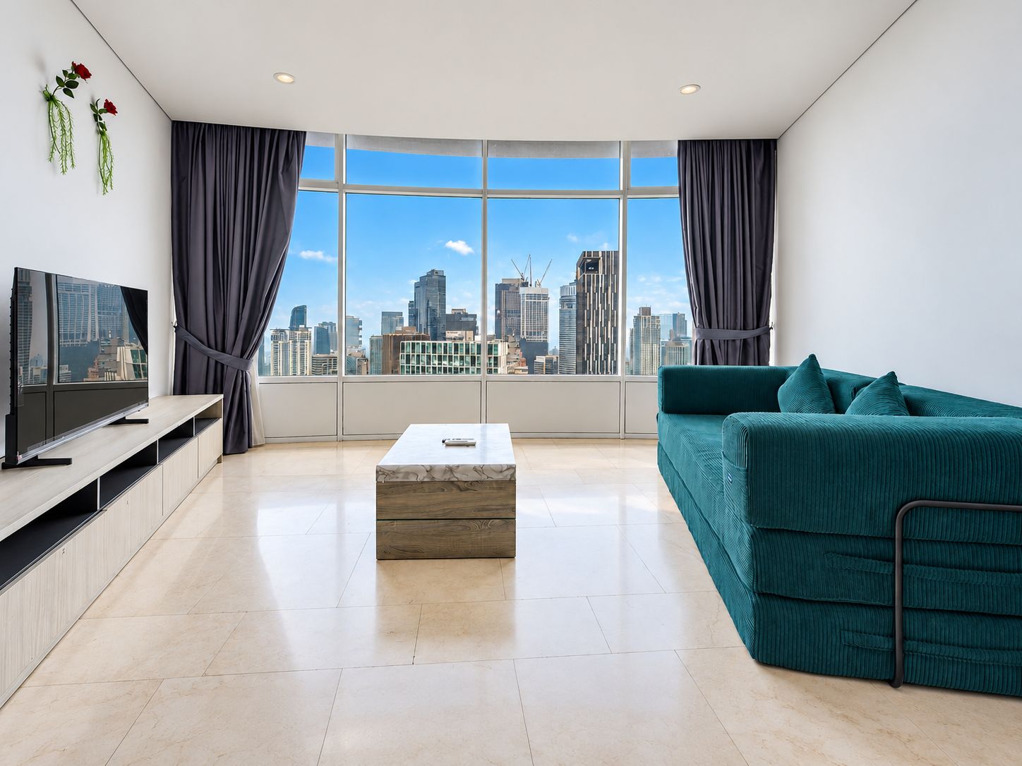 A modern living room with a city view, a flat-screen TV, a sofa, and a coffee table.