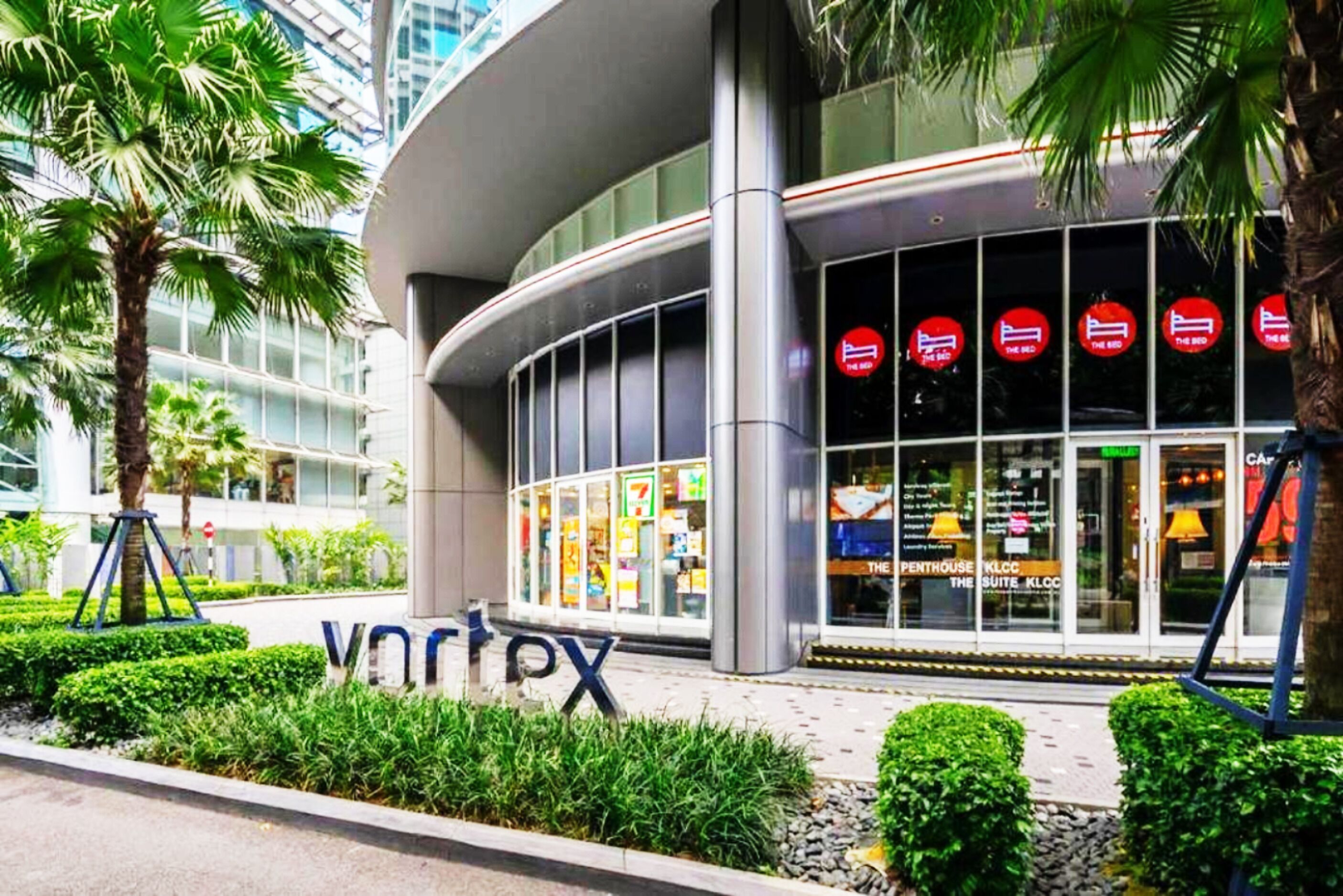 A modern building with a sign reading "vartex" and a glass facade displaying various advertisements.