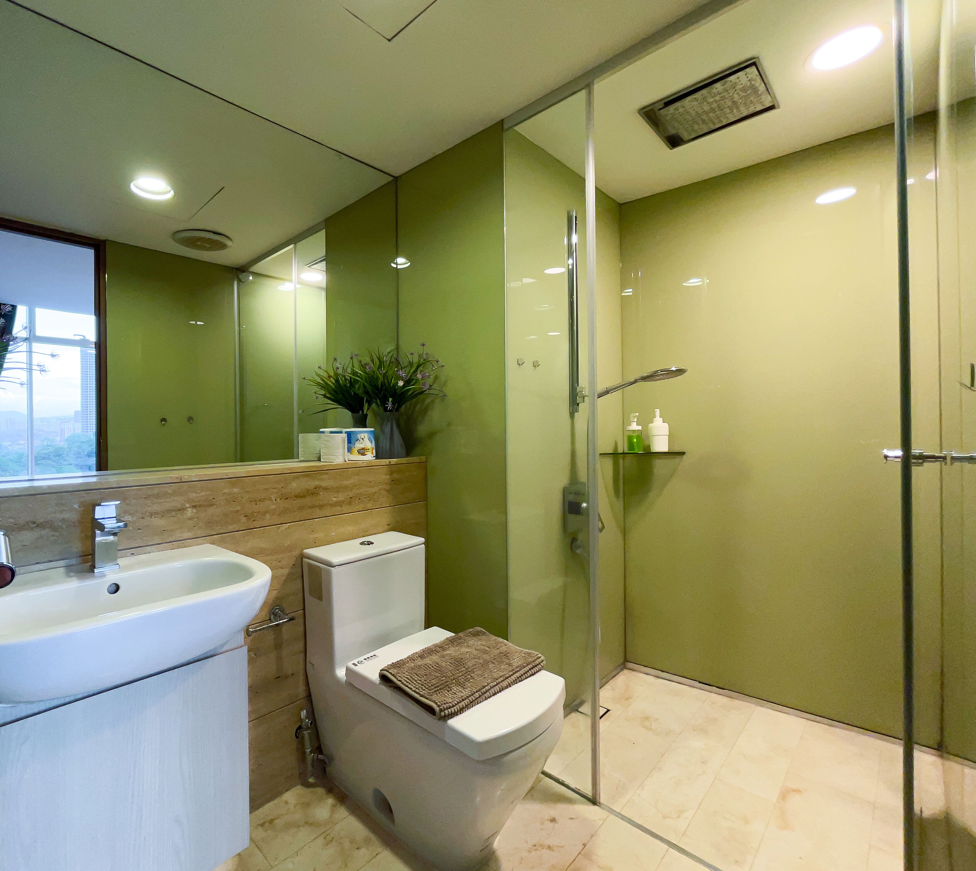 A modern bathroom with a glass shower enclosure, a toilet, and a sink.