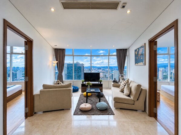 A modern living room with a city view, furnished with sofas and a coffee table. - Vortex Suites KLCC By BlackNest (Kuala Lumpur)
