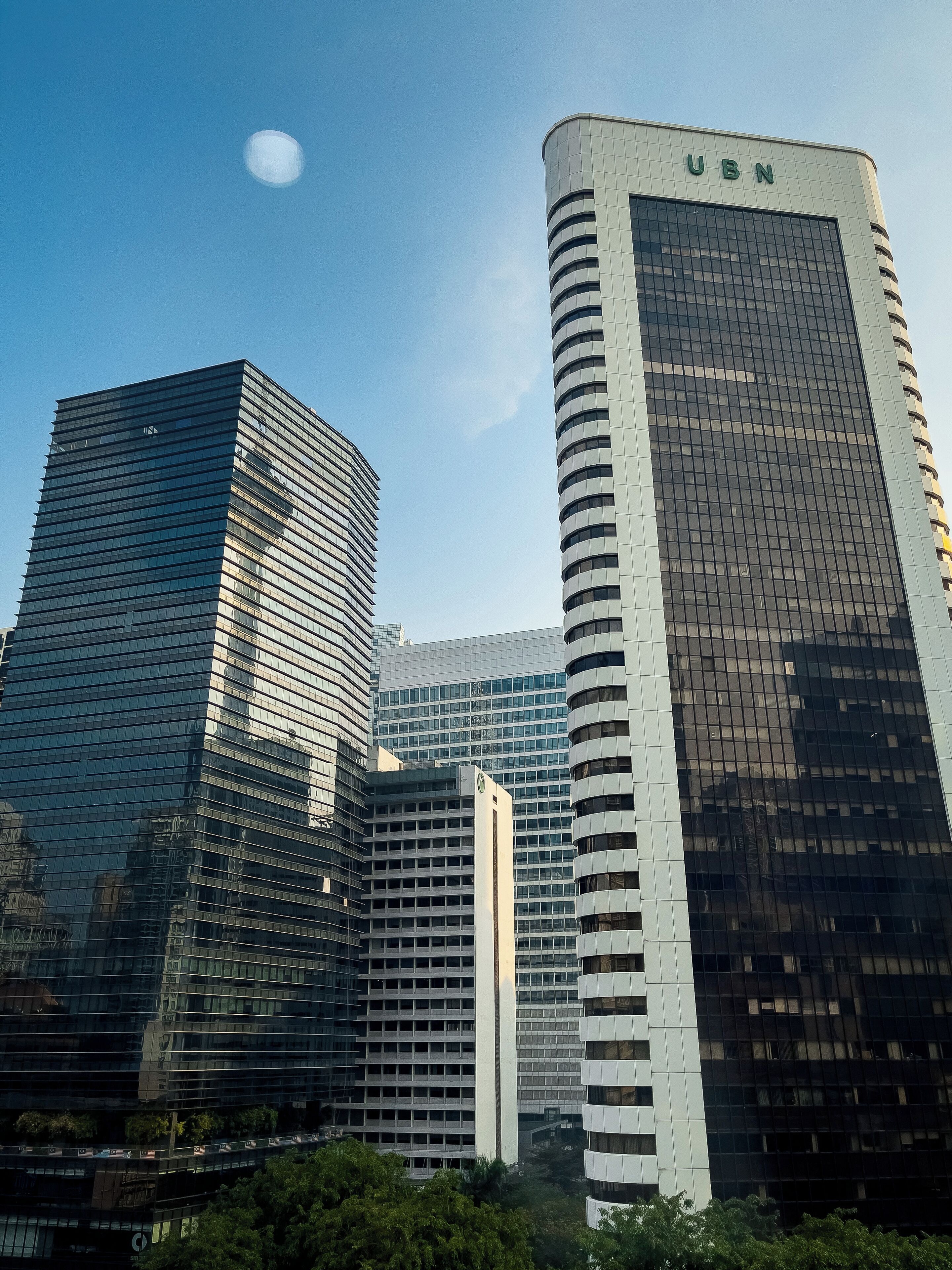 A cluster of modern high-rise buildings with reflective glass facades, one prominently labeled "UBN".