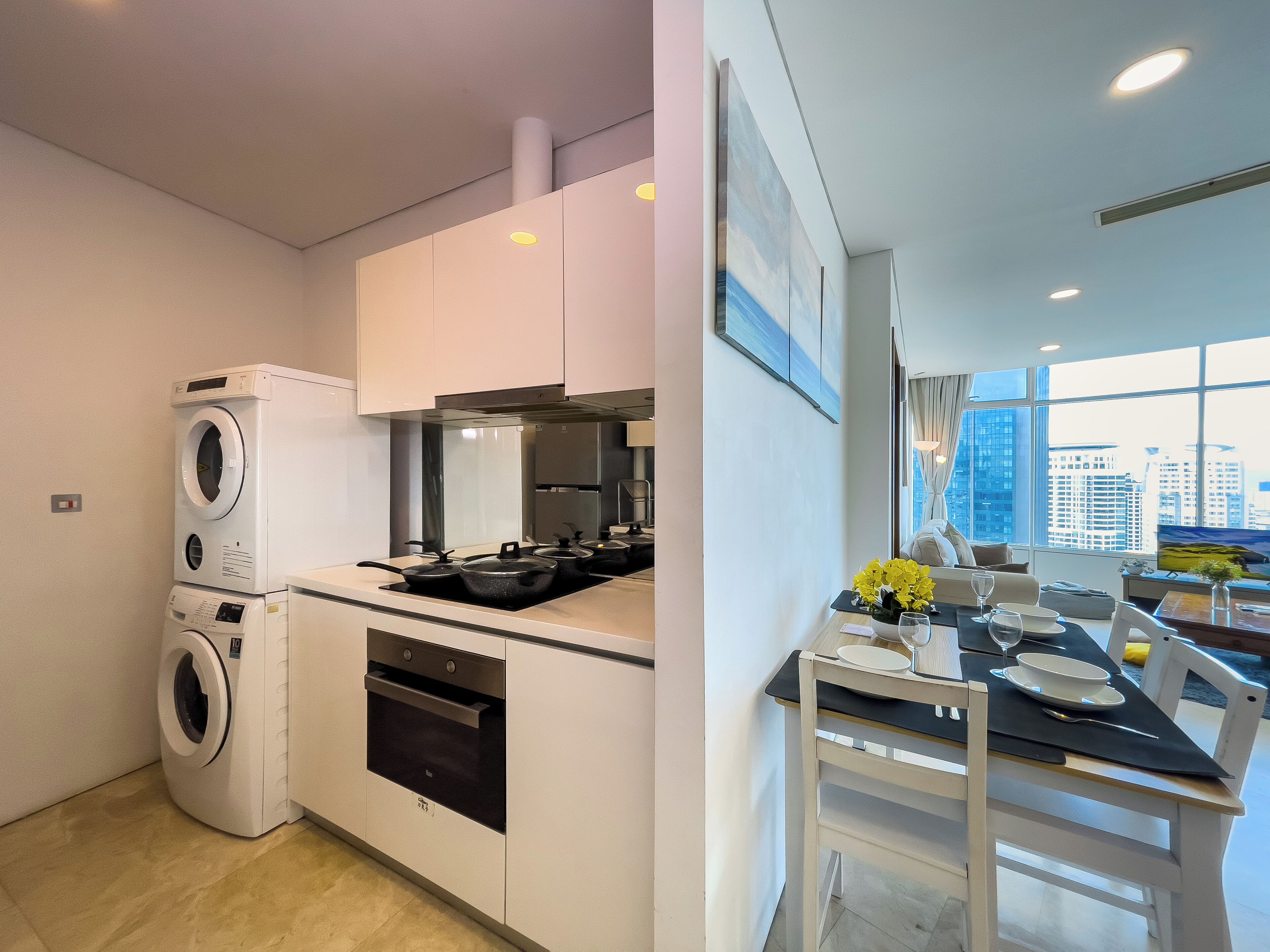 A modern kitchen with built-in appliances, a dining area with a view of the city, and a large window.