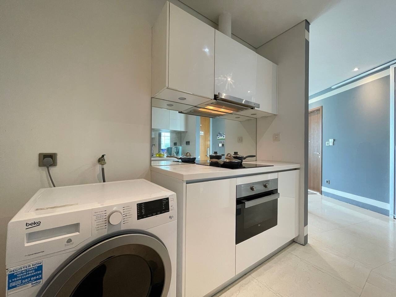 A compact kitchen with a washing machine, a stove, and a microwave.