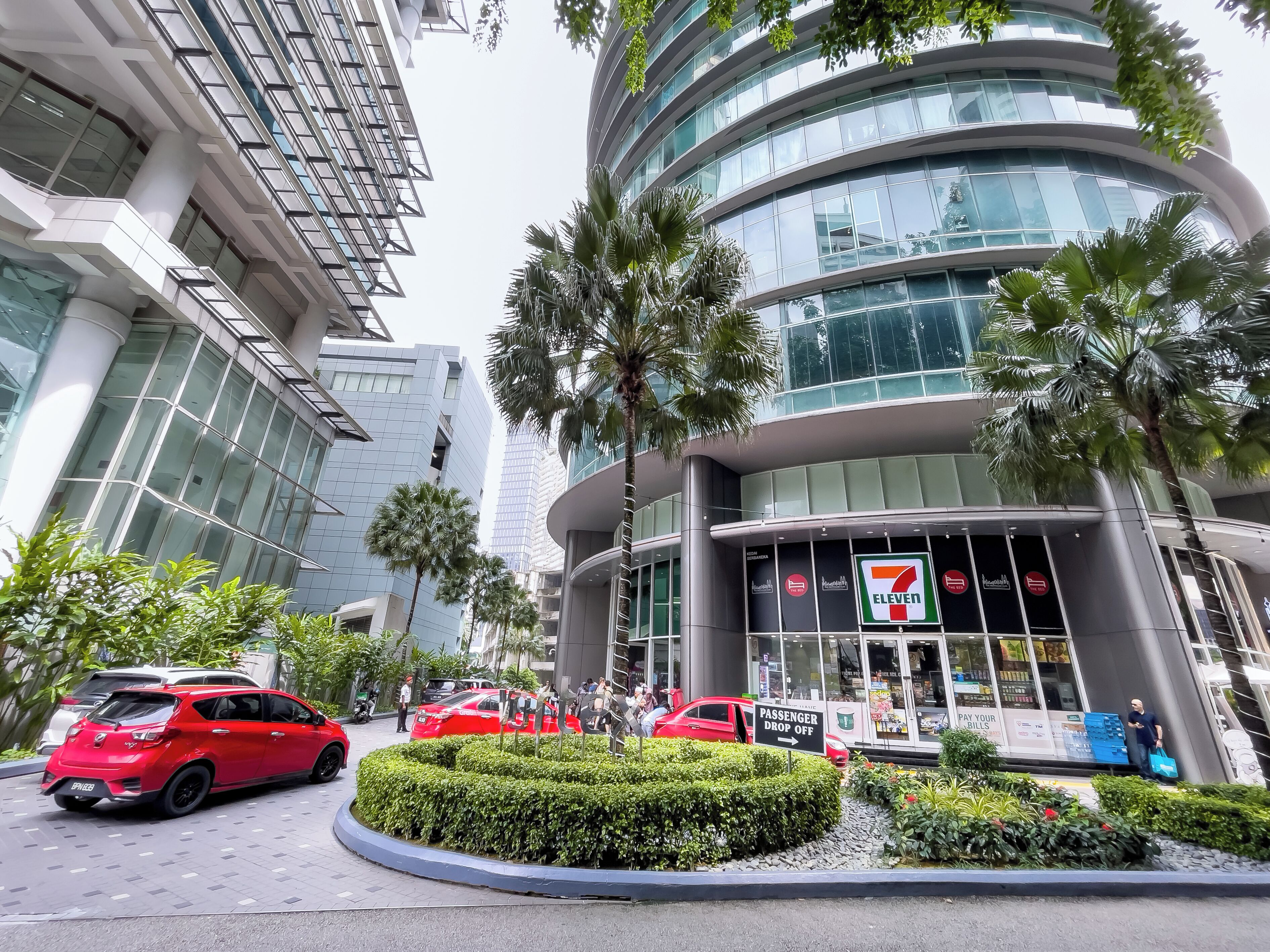 A 7-Eleven store with a modern design, surrounded by palm trees and other greenery.