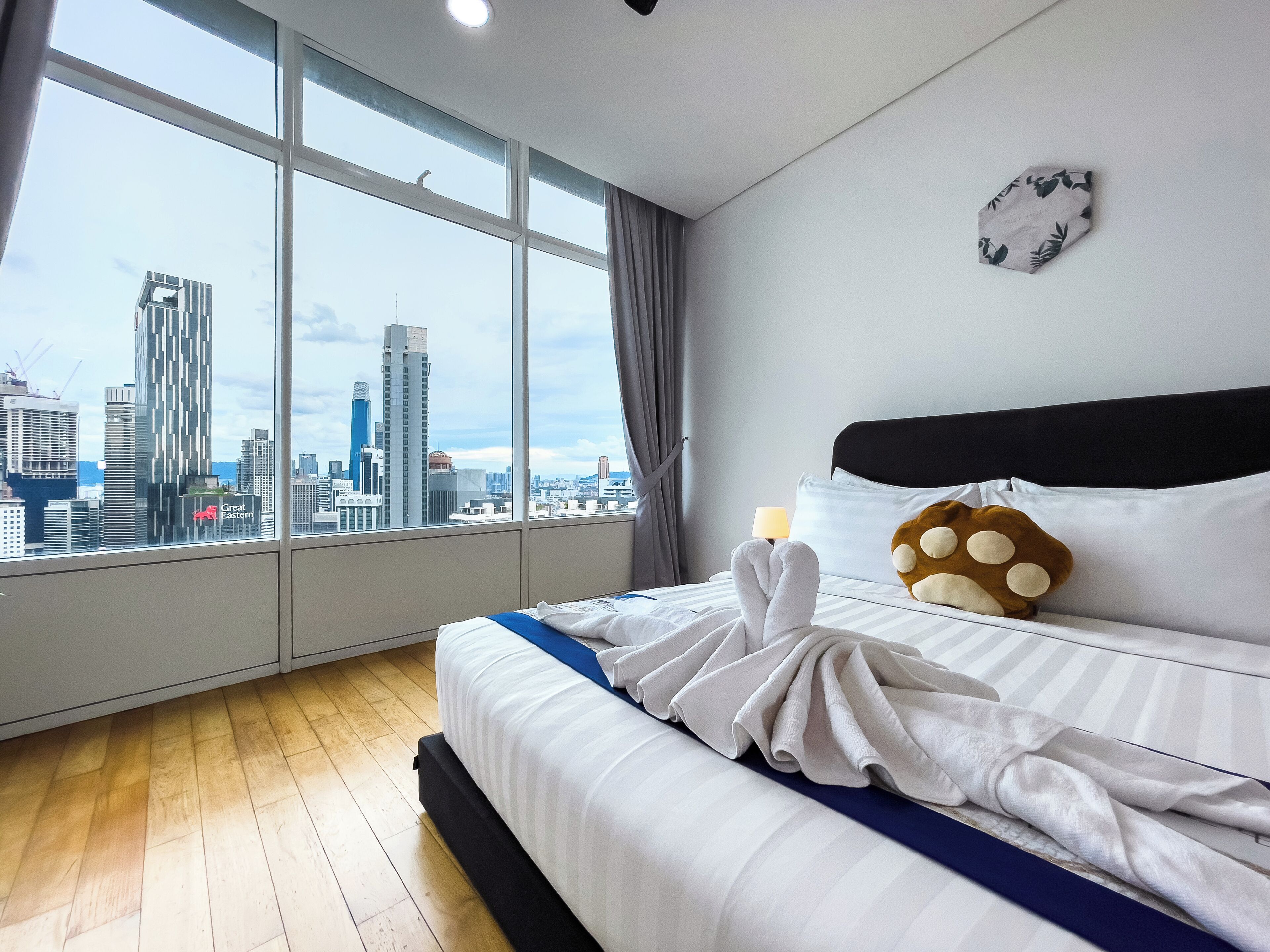Een hotelkamer met een groot raam, een bed met witte lakens, een kussen met een pootafdruk design en een klok aan de muur.