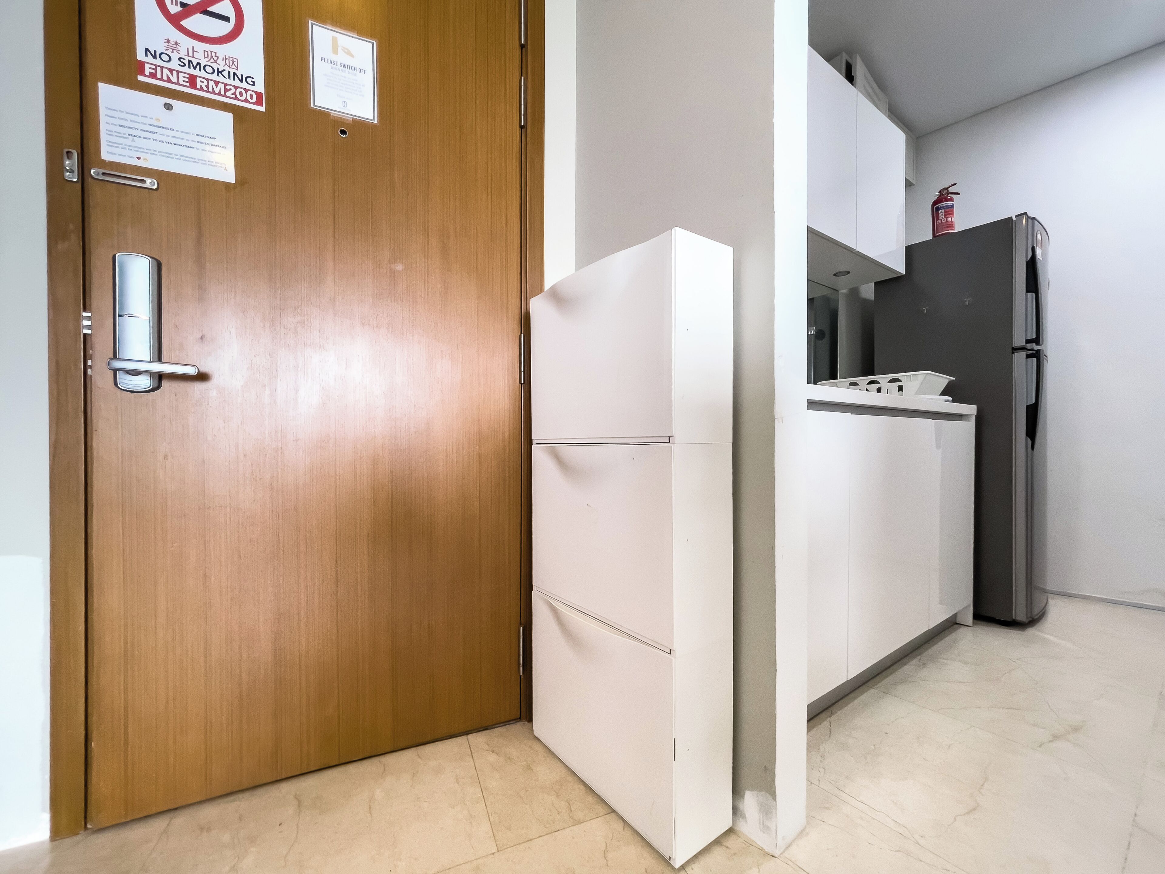 A kitchen with a wooden door, a white refrigerator, and a stainless steel stove.