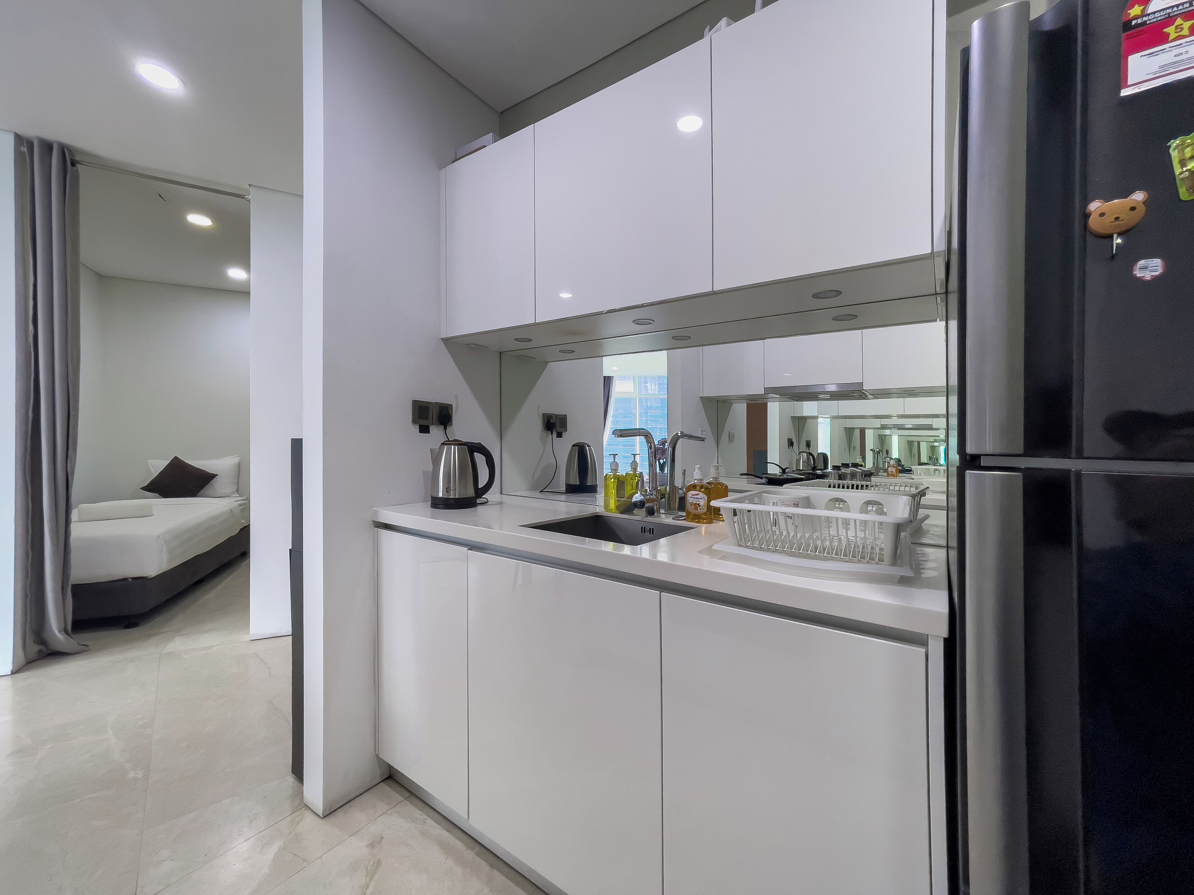 A modern kitchen with white cabinets, a black refrigerator, and a built-in oven.