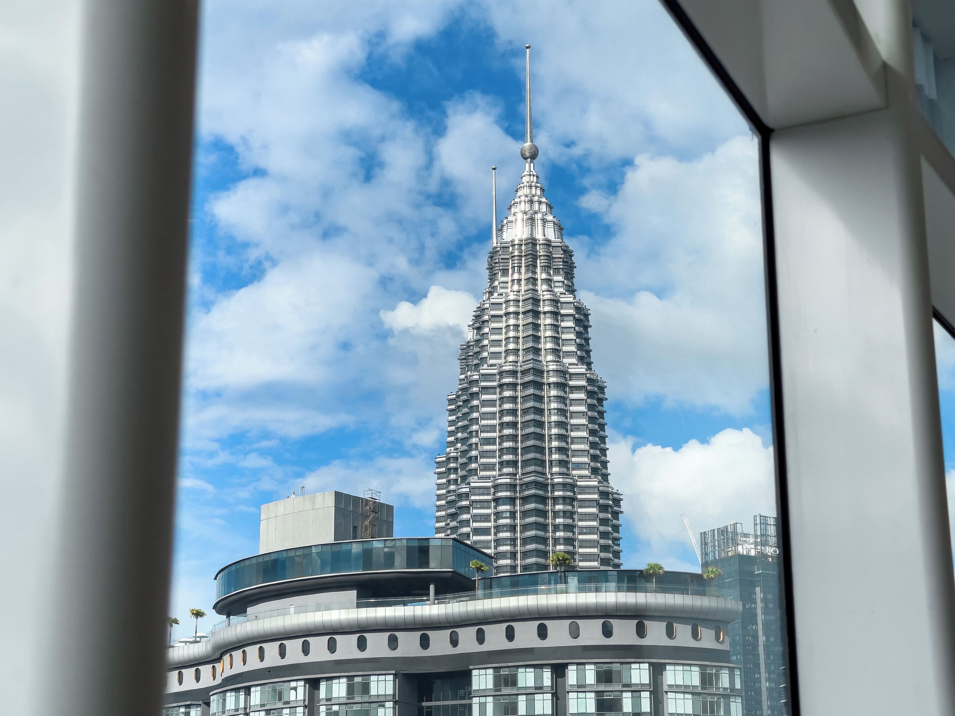 A high-rise building with a distinctive spire, surrounded by modern architecture.