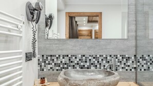 Un baño con un lavabo de piedra, un espejo y un secador de pelo montado en la pared.