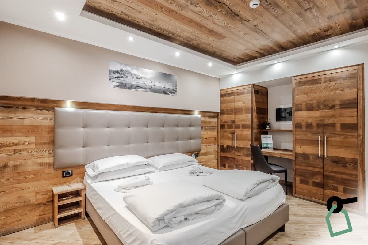 A modern bedroom with a large bed, wooden headboard, and built-in wardrobe.