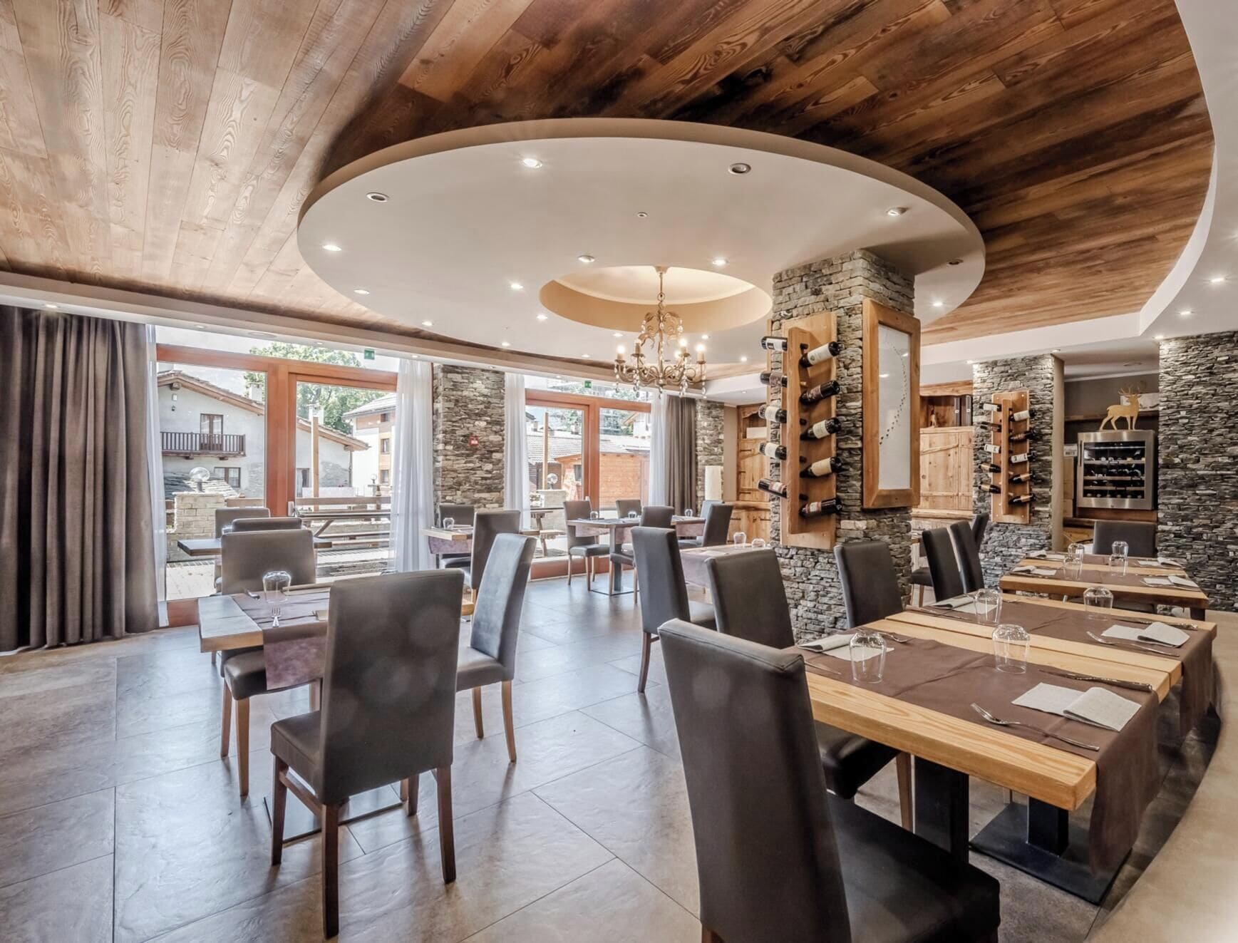 A restaurant with a stone wall, wooden ceiling, and a view of the outside.