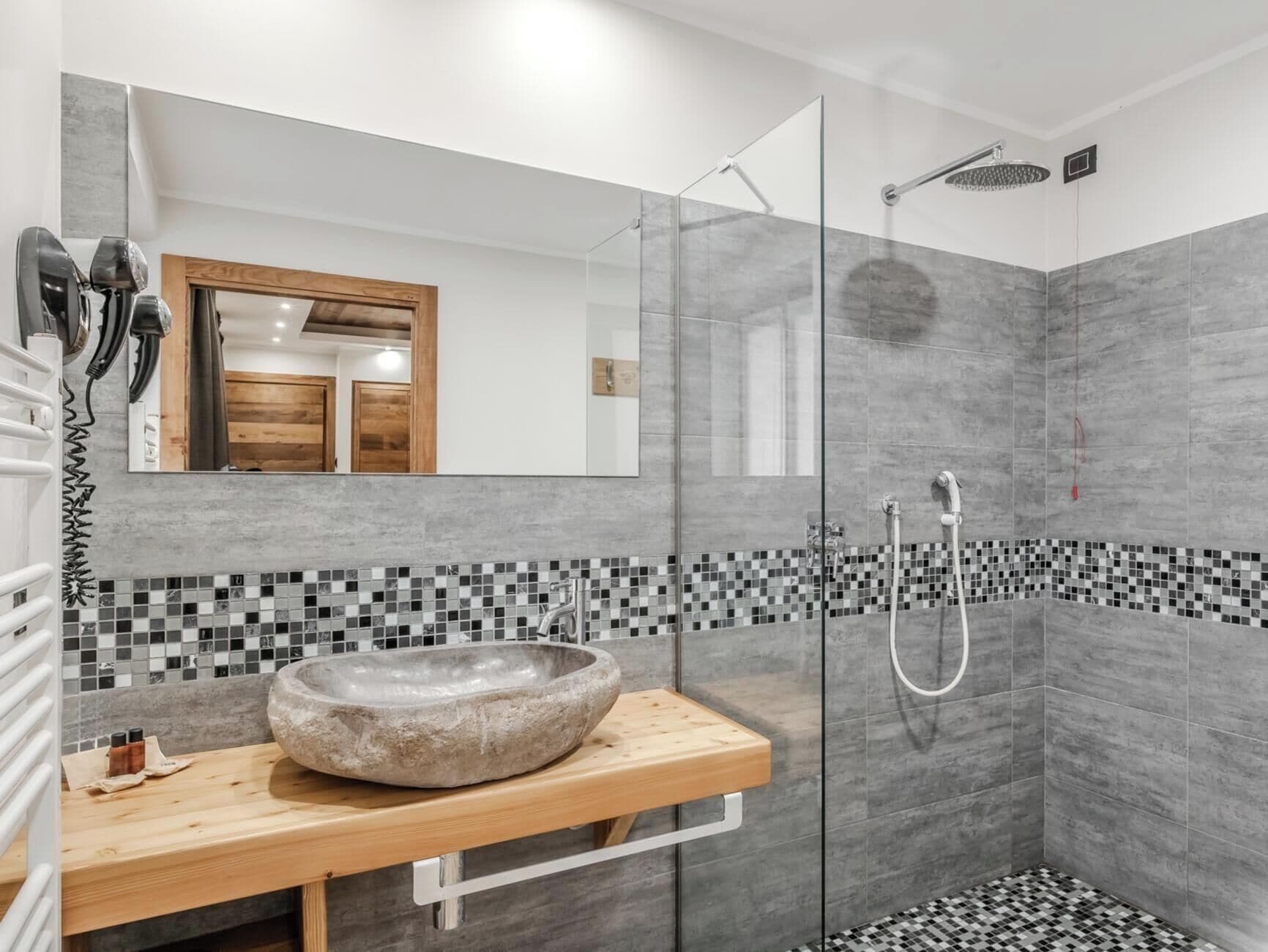 Une salle de bain moderne avec un lavabo en pierre, une douche en verre et un mur recouvert de carreaux.