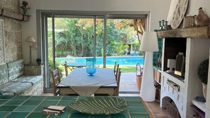 A dining area with a table, chairs, and a view of an outdoor swimming pool.