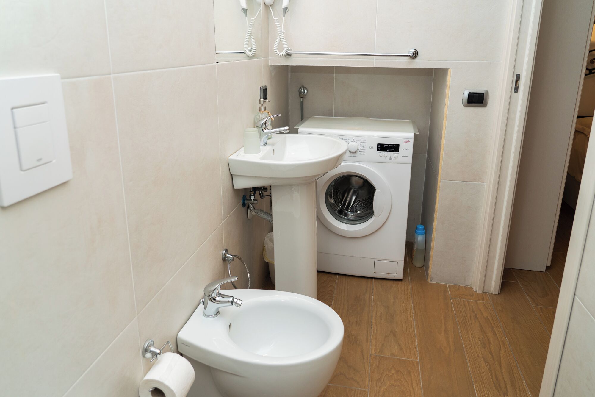 Een kleine badkamer met toilet, wastafel en wasmachine.
