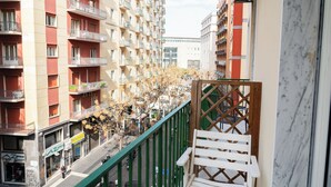 A balcony with a wooden lattice railing overlooking a street with parked cars and a building with balconies. - Suite Cervantes (Naples)