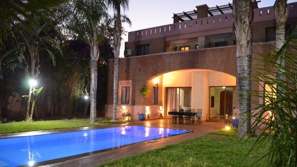 A modern building with a swimming pool, outdoor seating, and well-lit pathways. - Villa in the heart of Marrakech (Bab Ighl Marrakesh,)