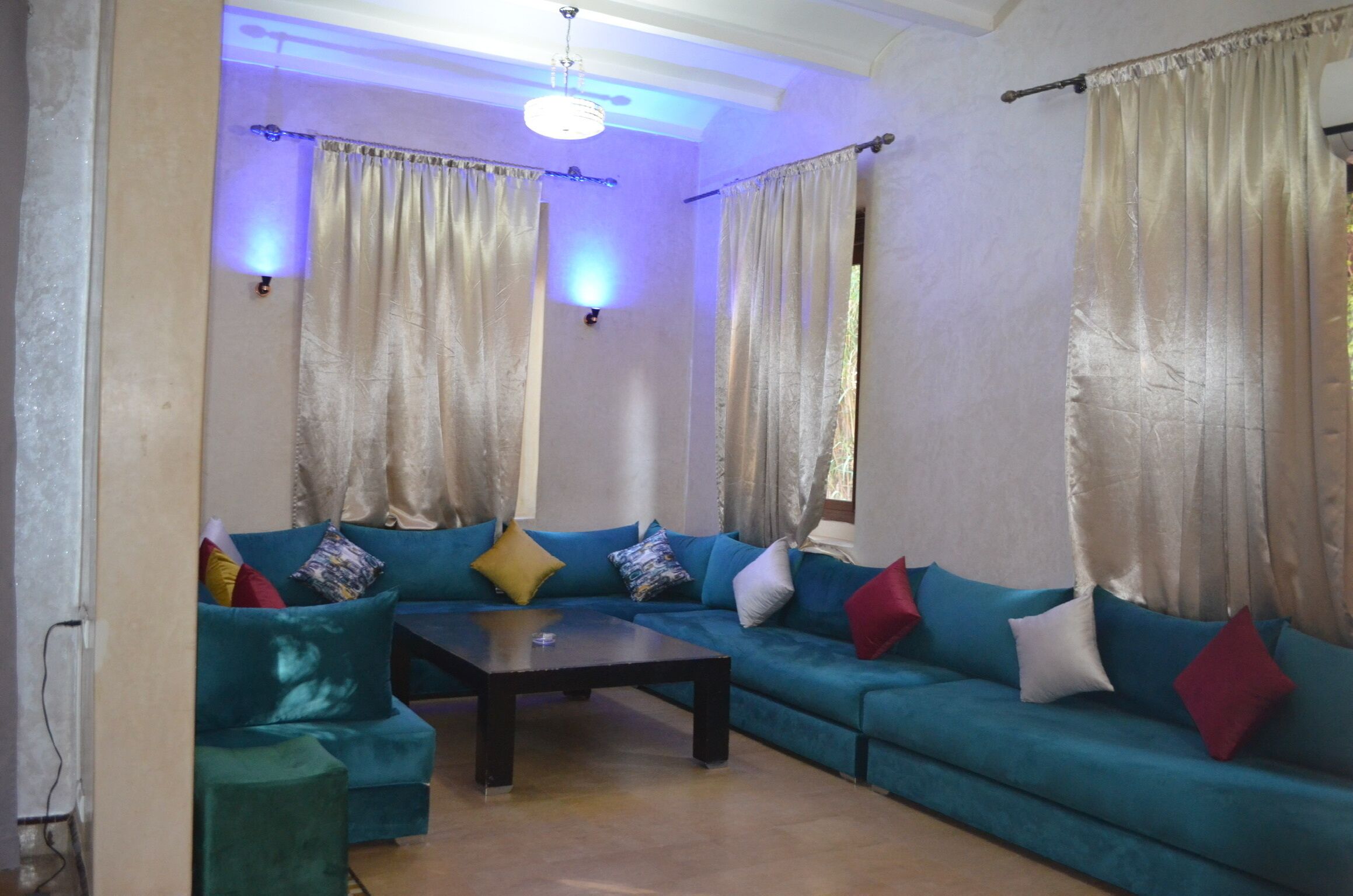 Un salon avec un canapé de couleur turquoise, une table basse et des rideaux.