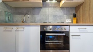 Een keuken met een inbouwoven, een roestvrijstalen afzuigkap en een moderne kraan.