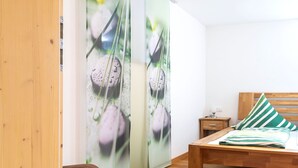 Een slaapkamer met een houten bed, een nachtkastje en een kussen met groene en witte strepen.