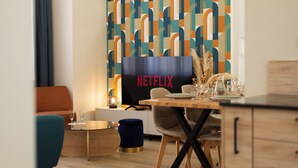 A modern dining area with a wooden table, chairs, and a television displaying 'NETFLIX'. - F3 au Coeur des Cordiers, Avec Parking Privatif Inclus (Le Tréport)