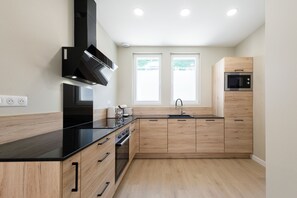 Une cuisine moderne avec des meubles en bois, un plan de travail noir, un four encastré et un four à micro-ondes.