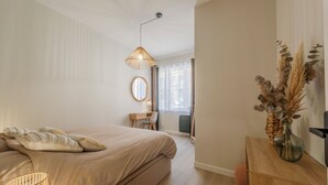 A bedroom with a bed, bedside lamp, and a wooden nightstand with a vase. - F3 au Coeur des Cordiers, Avec Parking Privatif Inclus (Le Tréport)