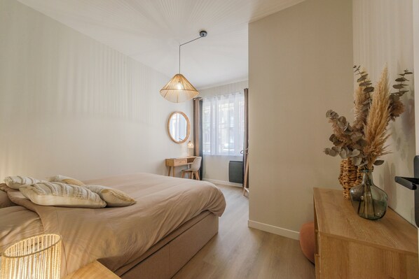 Une chambre à coucher avec un lit, une lampe de chevet et une table de chevet en bois sur laquelle est posé un vase.