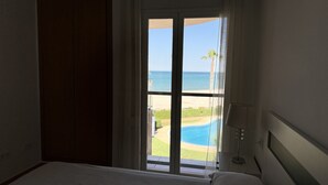 Ein Hotelzimmer mit großem Fenster mit Blick auf Strand und Pool.
