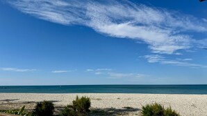 Ein Kiesstrand mit klarem Himmel und ruhigem Meer.
