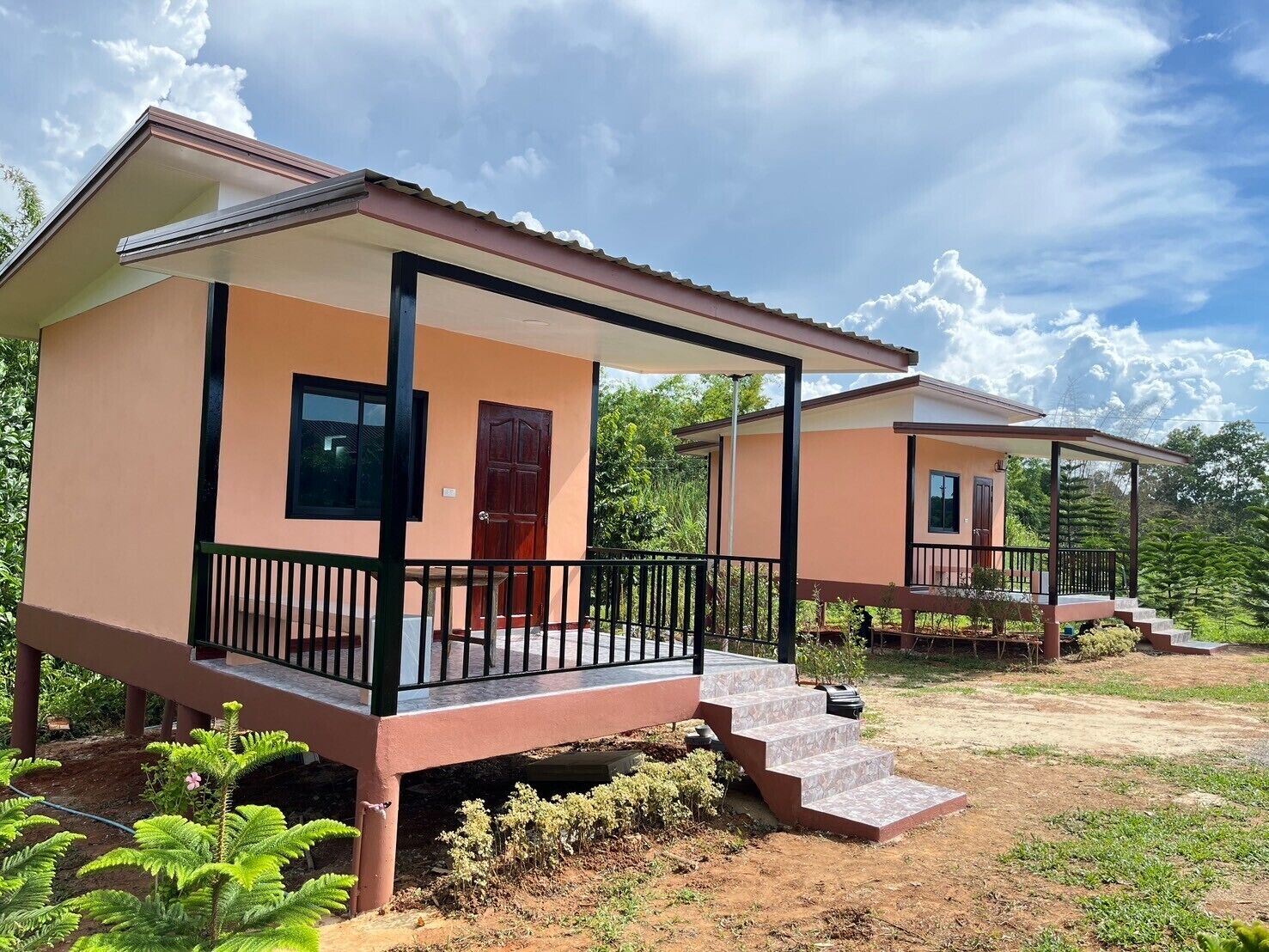 Um bangalô moderno com varanda, porta de entrada e escadaria que leva ao acesso.